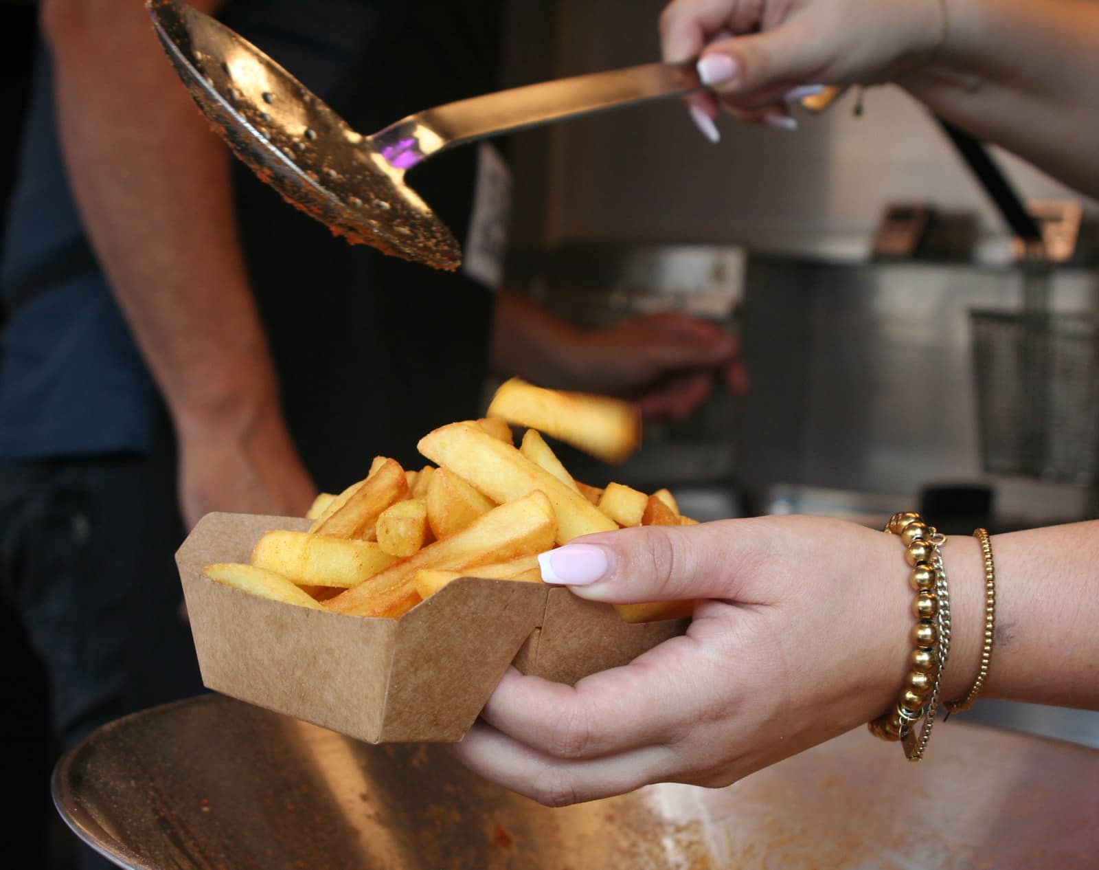 Friet valt van de schep in een kartonnen bakje