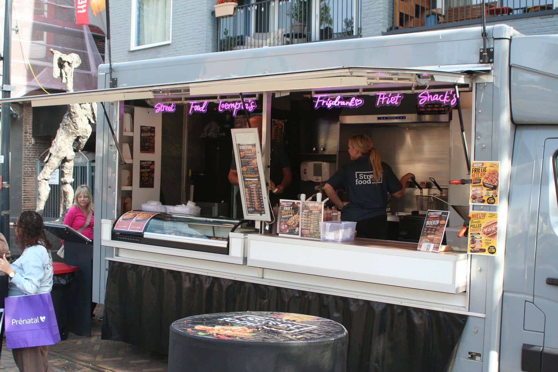 De foodtruck op de markt, met het team aan het werk achter het open luik