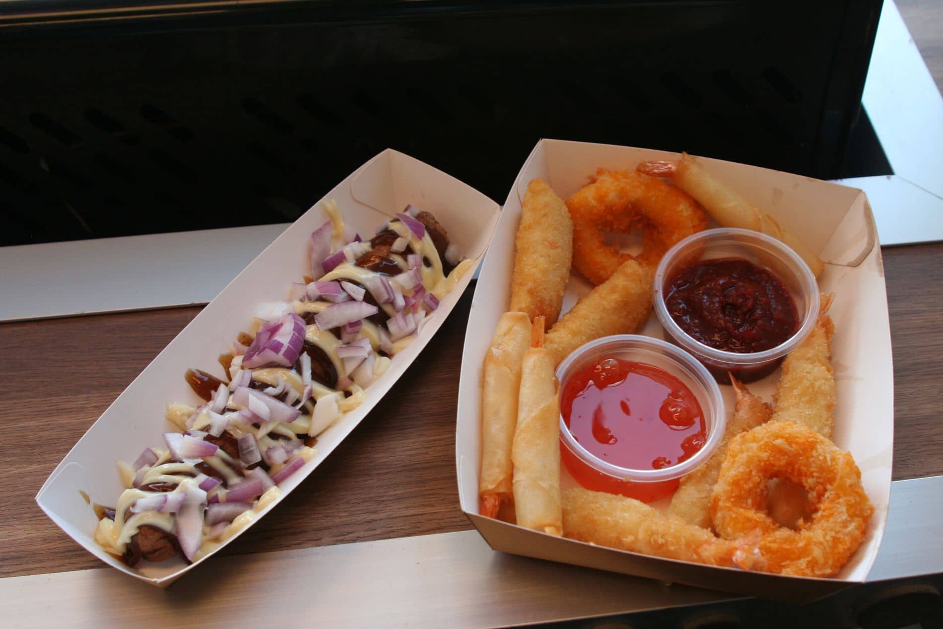 Een frikandel speciaal en een tapas bakje met sausjes naast elkaar