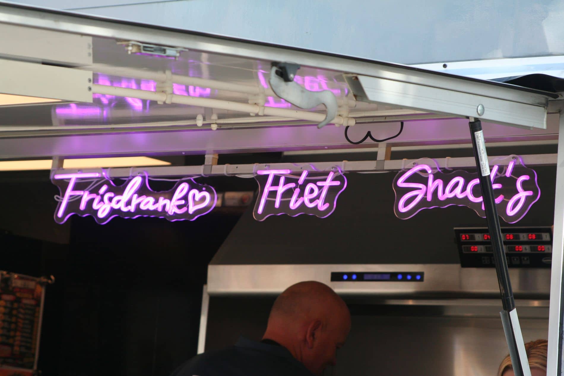 Roze neonletters boven de frituur: Frisdrank, Friet en Snack's