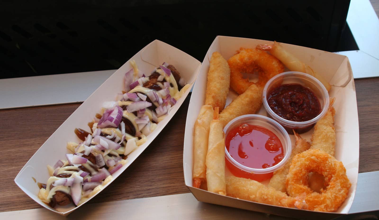 Een frikandel speciaal en een tapas bakje met sausjes naast elkaar