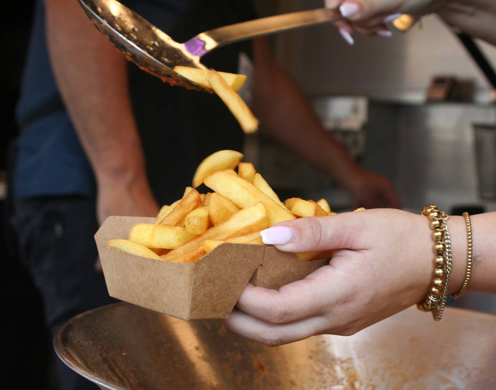 Verse friet valt van de schep in een kartonnen bakje