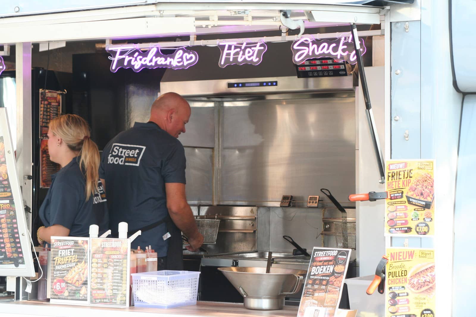Twee mensen aan het werk achter de frituur in de truck